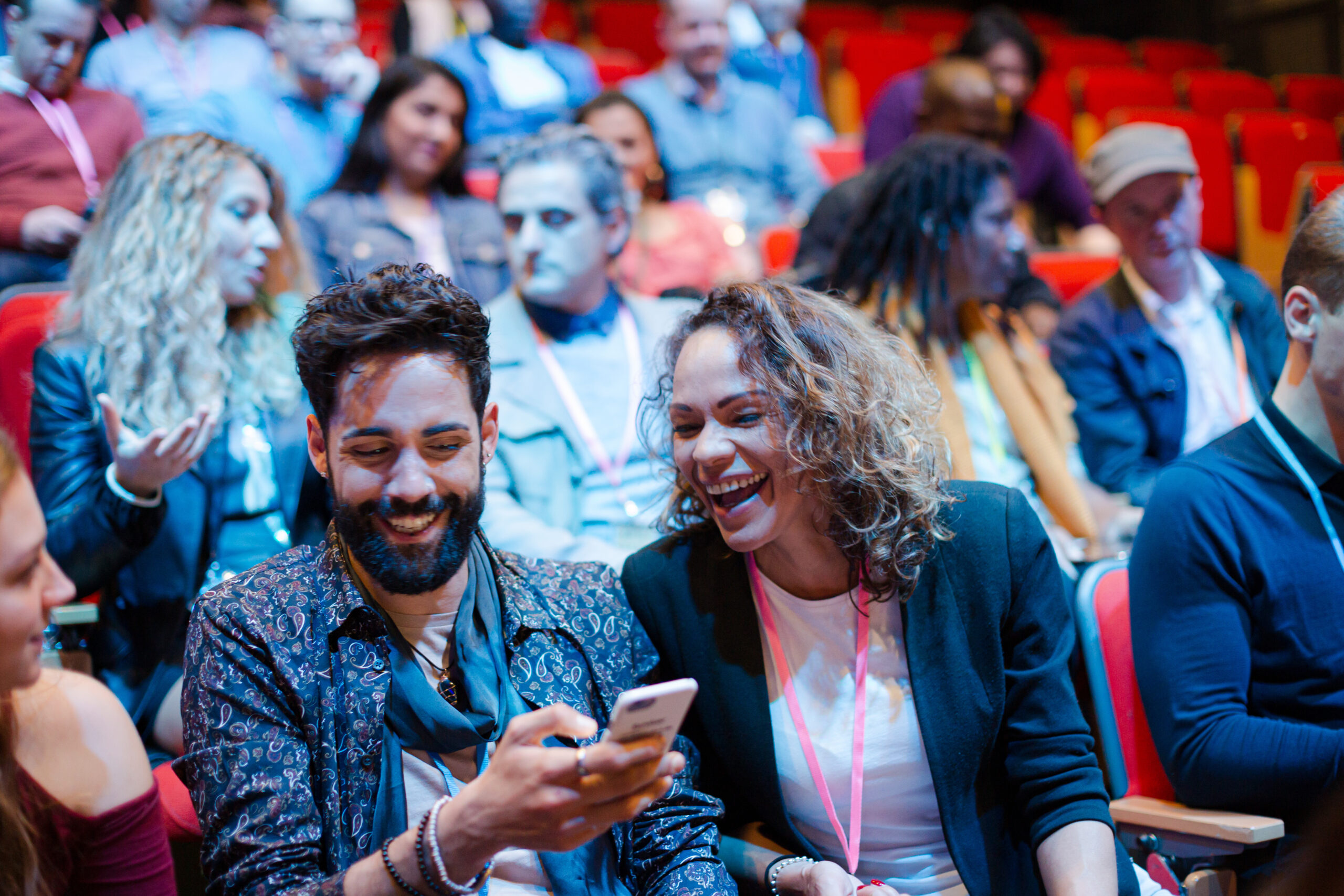 Man and woman with smart phone in conference audience